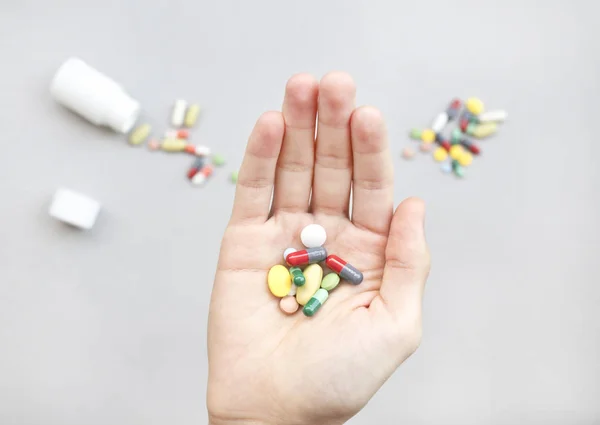 Elinde renkli haplar ve ilaçlar var.