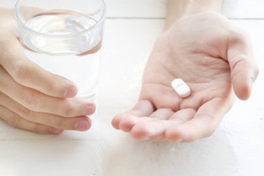  Beyaz hap ve bir bardak su adam elinde. Sağlık kavramı