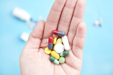 Elinde renkli haplar ve ilaçlar var.