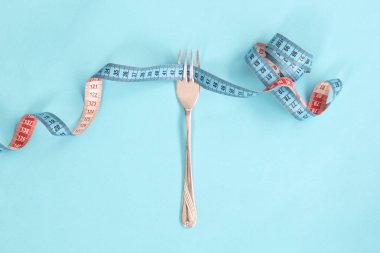 Kavram olarak çatal diyet için çevresinde şerit metre. Çatal mavi mavi arka plan kasette ölçme sarılı.