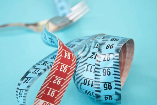 Kavram olarak çatal diyet için çevresinde şerit metre. Çatal mavi mavi arka plan kasette ölçme sarılı.