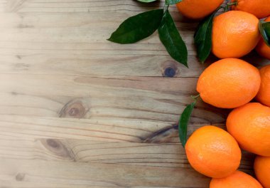 Portakal ile ahşap bir masa yapraklarda. Kopya alanı ile üstten görünüm.