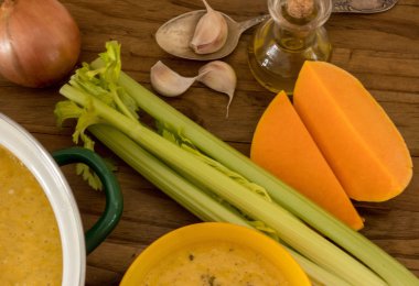 Maydanoz koyu ahşap masa selery, garlick ve kabak parçaları üzerinde kabak ve havuç çorbası