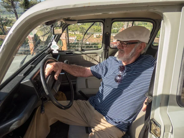 Homem mais velho sorrindo sentado em seu carro em dia ensolarado — Fotografia de Stock
