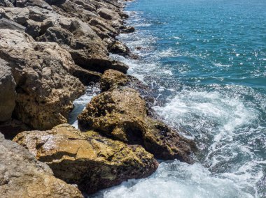 Deniz dalgaları isabet ve ortaya çıkan birkaç kahverengi taşlar üzerine sıçrama f