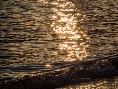 Gün batımında sahilde deniz dalgaları yakın