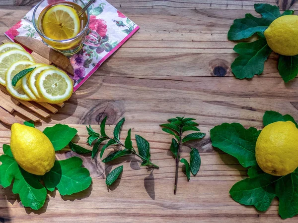 Ahşap üzerinde tam ve dilimlenmiş taze limon ile yeşil çay Fincan