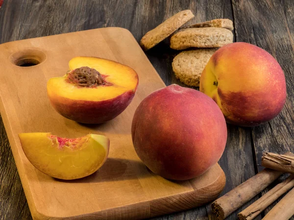 Персики и домашнее печенье на тёмном деревянном столе . — стоковое фото