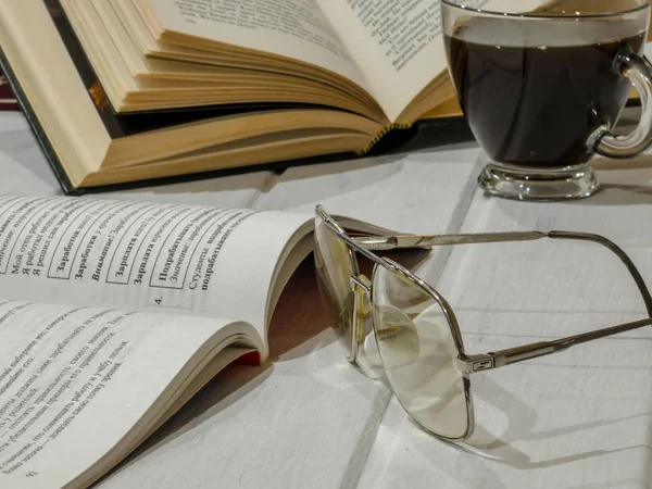Otwarte książki z okularami do czytania, filiżanką kawy na stole — Zdjęcie stockowe