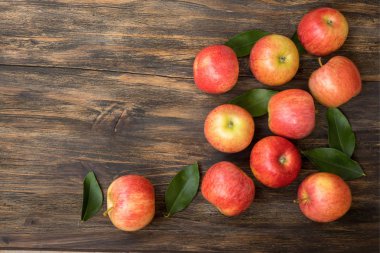 Ahşap masa üzerinde yeşil yaprakları ile kırmızı ve pembe elma , yakın u