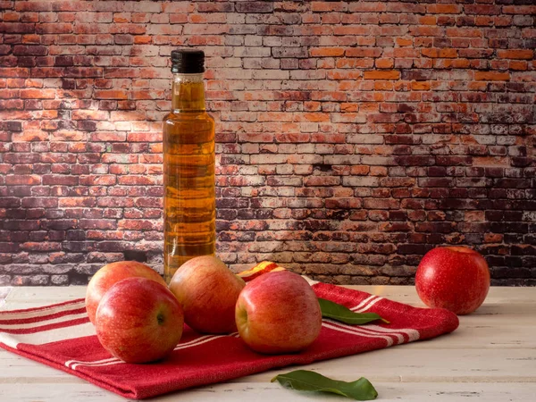 Apple vinegar in glass bottle and fresh red apples on   wooden t