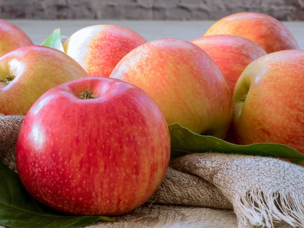 Rote und rosa Äpfel mit grünen Blättern auf Leinwand, Nahaufnahme — Stockfoto