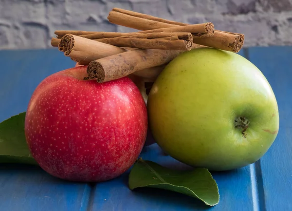 Two fresh apples, red and green, and cinnamon sticks on the blue — Stock Photo, Image