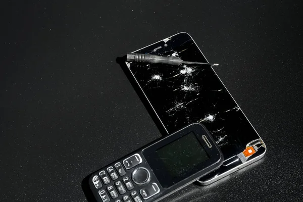 Repair phones with a broken screen on a dark background.