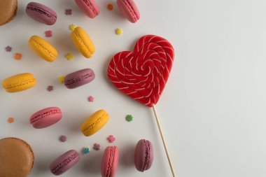 Pasta macaron veya beyaz arka planda, karamel bir kalp, üstten görünüm renkli badem çerezler acıbadem kurabiyesi. Sevgililer günü kavramı