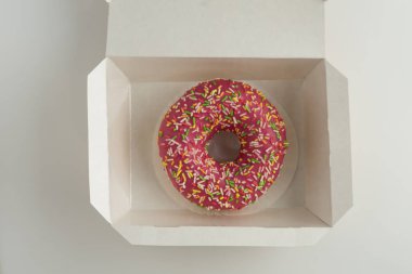 Bir kutu içinde beyaz arka plan üzerinde izole buzlanma ile bir çörek