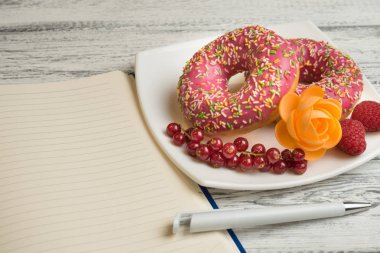 Buzlanma ve çilek yanına tabakta donut yatıyor çörek tarifleri kaydetmek için bir not defteri