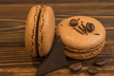 Çikolatalı badem macaroons kahve fasulye, koyu ahşap masa ile. Tatlı macaroons ile bir parça çikolata. Üstten görünüm