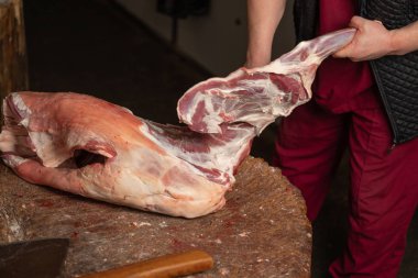 Kasap kasap bıçağı kuzu kesmeye çalışır.