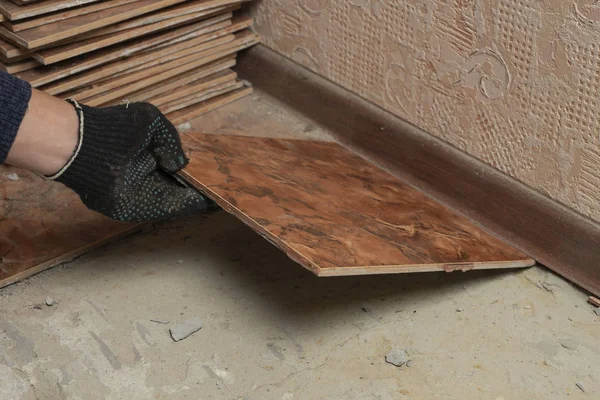 Floor tiles installation. A man installs ceramic tile, renovation in progress