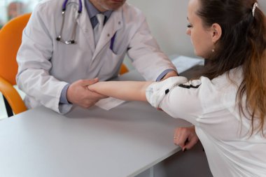 Doktor kadın hastanın derisini muayene ediyor..