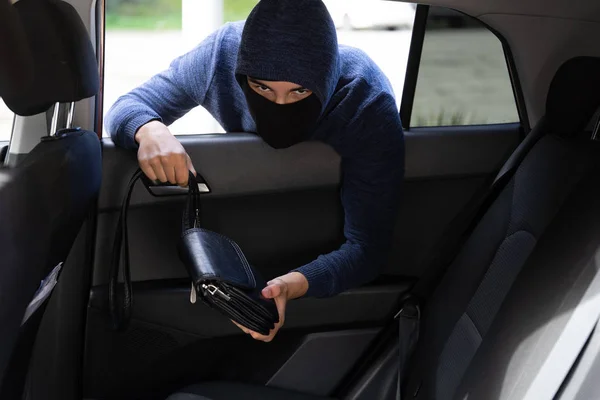 En tjuv som stjäl handväska från bilen. Transport brott koncept — Stockfoto