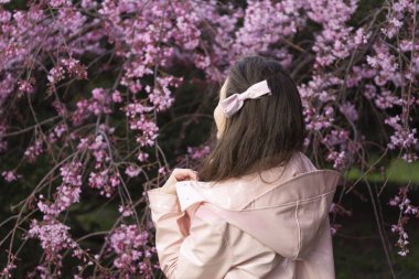 Vintage genç kadın arkadan görünüm üzerinde bir çiçek bahçesi yürüyor.