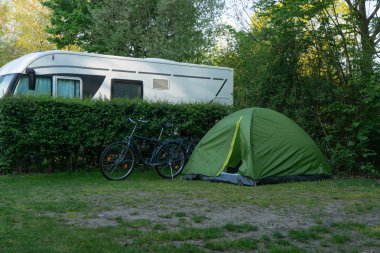 Orman arka plan üzerinde yeşil çim üzerinde bisiklet ve römork yakınındaki kamp çadırı, Avrupa kamp, turistik yaşam