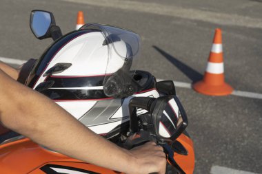 İki el motosikletin direksiyonuna tutunuyor. Motosiklet kaskmotokros bisiklet üzerinde yatıyor
