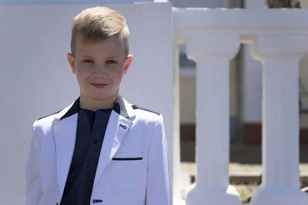 Mode et style pour enfants. Un beau garçon, modèle de mode dans une élégante veste blanche pose pour appareil photo — Photo