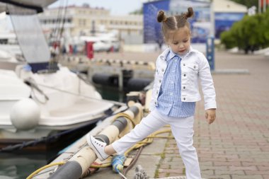 Marinada şık ve şık kıyafetler giymiş küçük kız modeli. Çocuk çocukların eşyalarının reklamını yapmak için bir fotoğraf çekimine katılıyor.