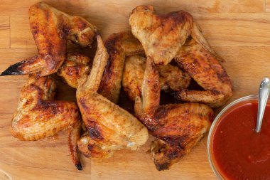 Ahşap masada kırmızı soslu tavuk kanatları