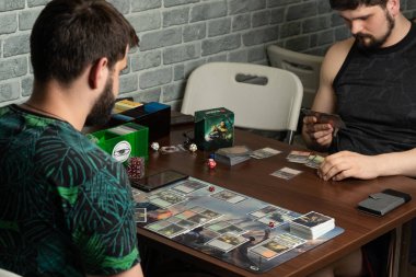  İki sakallı hipsters masa oyunu The War of the Spark Magic The Gathering yatıyor yeni bir parçası oynuyor