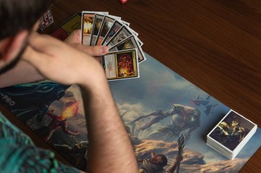 Young hipster with a beard holding Magic cards The Gathering