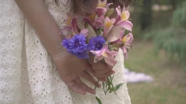 女の子は後ろに花束を隠します スローモーション — ストック動画