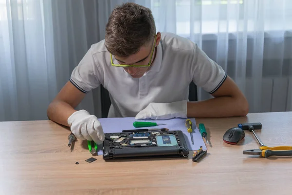 Laptop repair at home. Smart teen is repairing pc