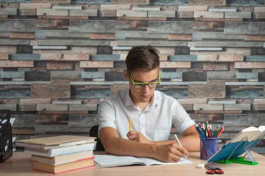 Evde oturan genç çocuk evde ev ödevi yapıyor