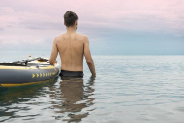 Sörf çocuk sörf hazırlanıyor. Sahilde sörf tahtası olan genç bir adam. Sörfçü ve deniz