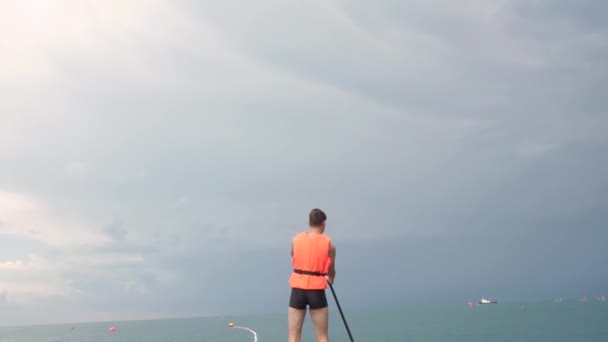 Jonge Man Sup Board Een Reddingsvest Achtergrond Van Zee Uitzicht — Stockvideo