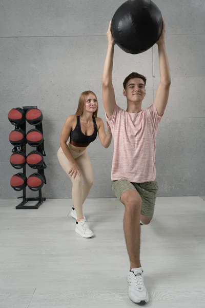 Sportliches Fitness-Paar bei Übungen mit Medizinball in der Turnhalle. Fitball-Training — Stockfoto