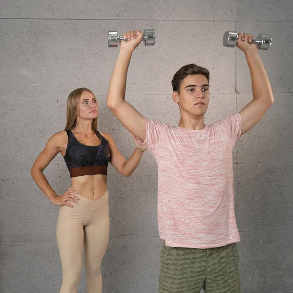 Pareja deportiva haciendo ejercicios con pesas en el gimnasio. Entrenamiento — Foto de Stock