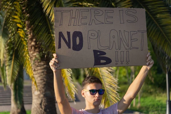 The phrase - There is no planet B drawn on a carton banner in young man\'s hand. Single picket or rally in defense of the environment. Global warming