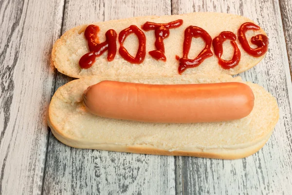 Hot dog főtt kolbásszal könnyű fa háttéren. A felirat ketchup Hot-dog. Első látásra. Makró — Stock Fotó