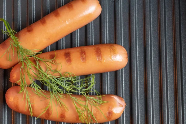 Tree grilled pork sausages with green dill on an electric grill. BBQ. Barbecue food close-up — Stock Photo, Image