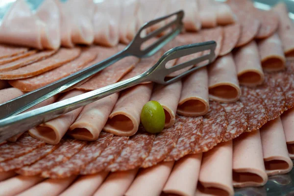 Cutting sausage and cured meat on a celebratory table. Snack with delicious French and Italian salami