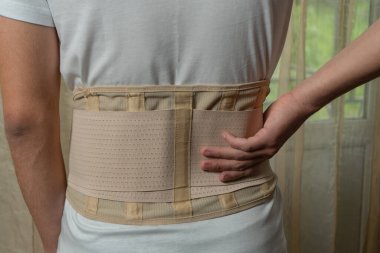 Lumbar brace on the human body. Trauma of back. Back brace, orthopedic lumbar, support belt for back muscles
