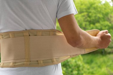 Back support for muscle back. Man wearing orthopedic brace to support core and lower back, rear view