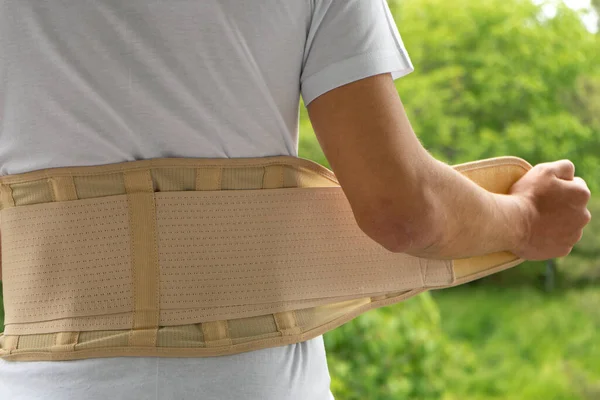 Back support for muscle back. Man wearing orthopedic brace to support core and lower back, rear view