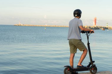 Tatilin boyunca deniz kıyısında elektrikli scooter kullanmak. Şehirde çevre dostu hareketler