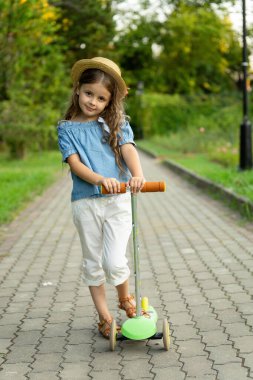 Çocuk plastiği tasviri bir scooter. Açık havada aktif çocuk eğlencesi var. Mobilete odaklan.